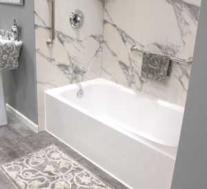 New white bathtub with white and grey marbled shower walls and chrome fixtures
