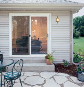 Sliding patio doors with steps underneath, leading to a stone patio area