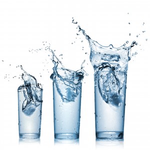 Three glass cups with water splashing out of them.