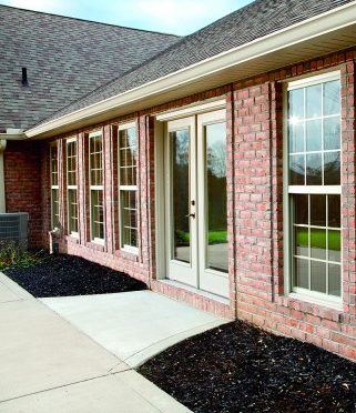 Cream french doors surrounded by windows on home with brick exterior