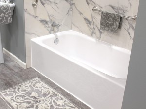 White bathtub with marbled walls and silver accents.