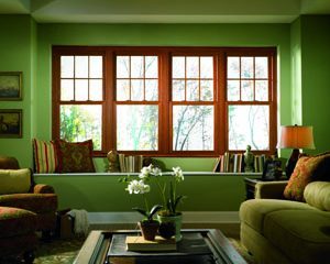 Large green living room with four beautiful, double-hung wood windows.